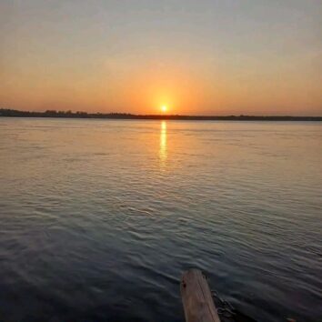 Sunset over calm ocean waters with the sun low on the horizon