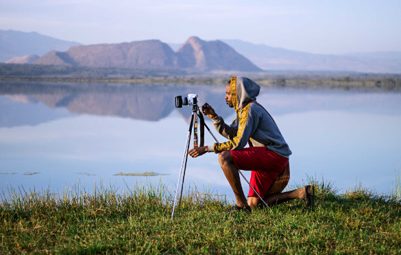 A man photographs wildlife by a lake in Kenya