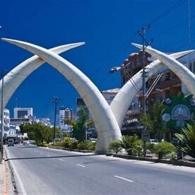 The Mombasa Tusks, four crossed elephant tusk sculptures arching over a city road under a blue sky
